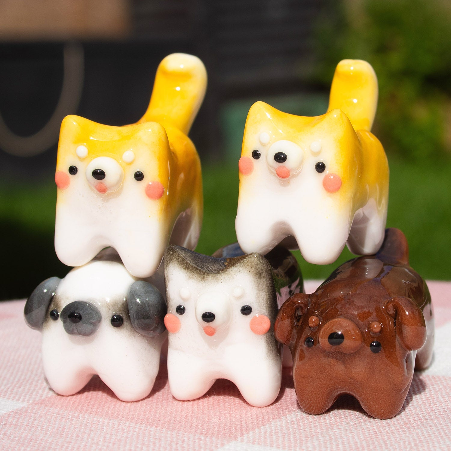 An assortment of cute polymer clay cat figurines, all hand painted in different colours, arranged on a wood slice